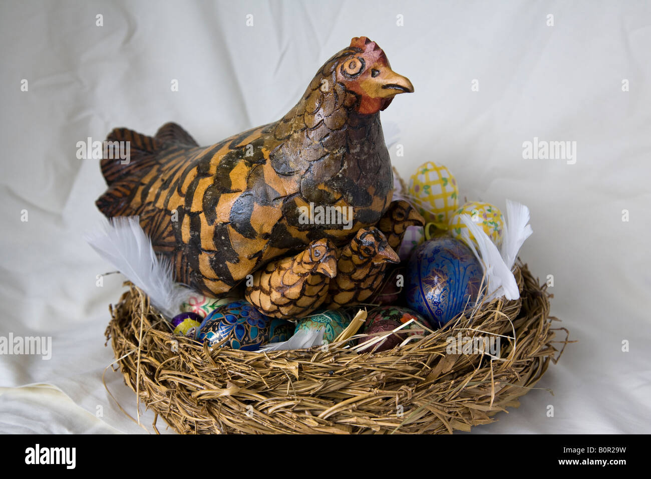 Ein Oster-Deko, handgeschnitzten Huhn und Küken dekorative Eier in einem Nest, Surrey, England. Stockfoto