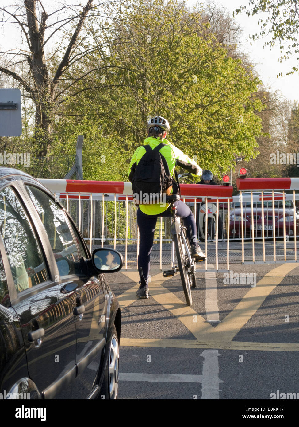 Radfahrer auf einem Bahnübergang warten, während die Barriere für das Bestehen eines Zuges ausfällt. Stockfoto