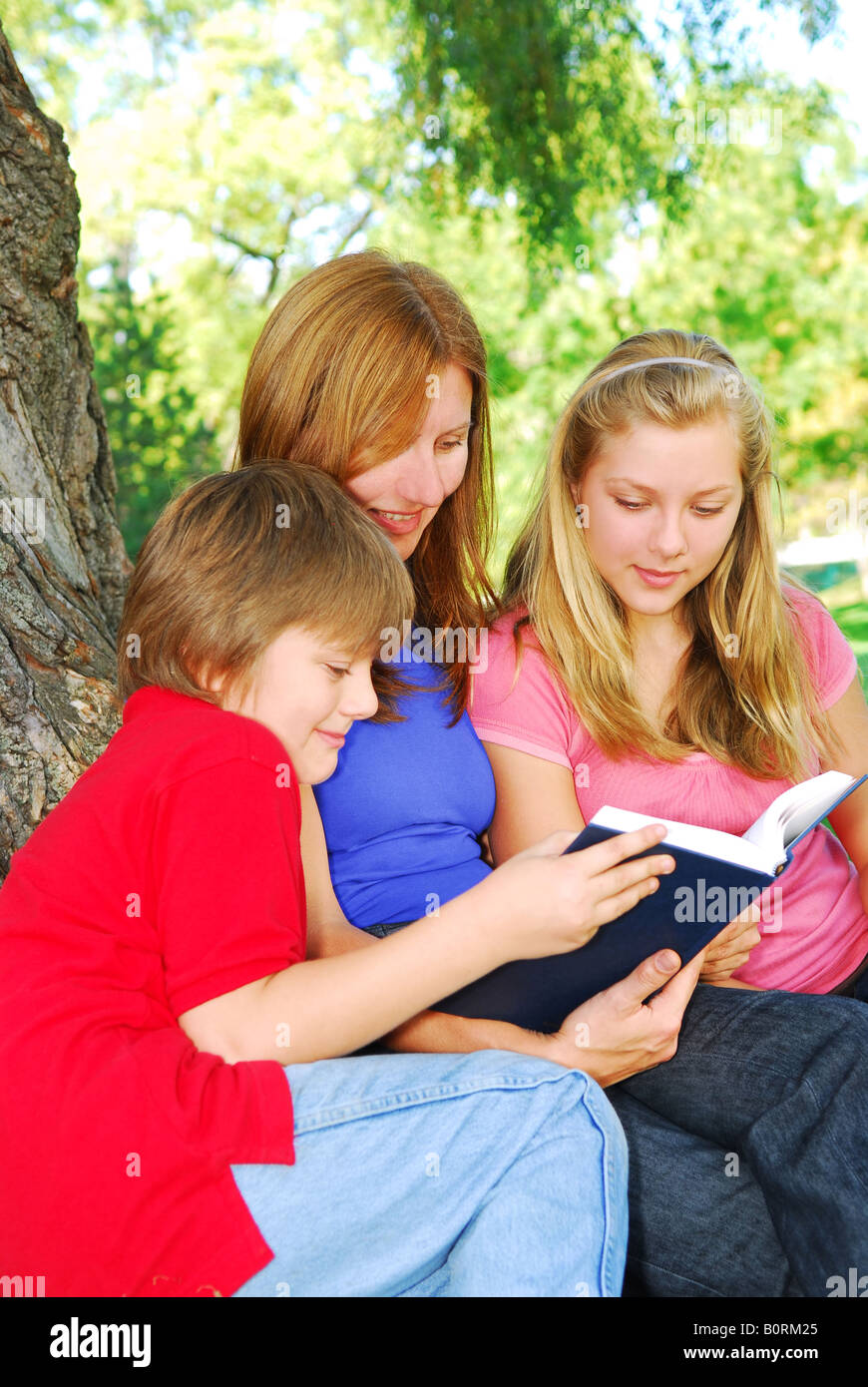 Porträt einer Familie Mutter und Kinder lesen ein Buch in einem park Stockfoto