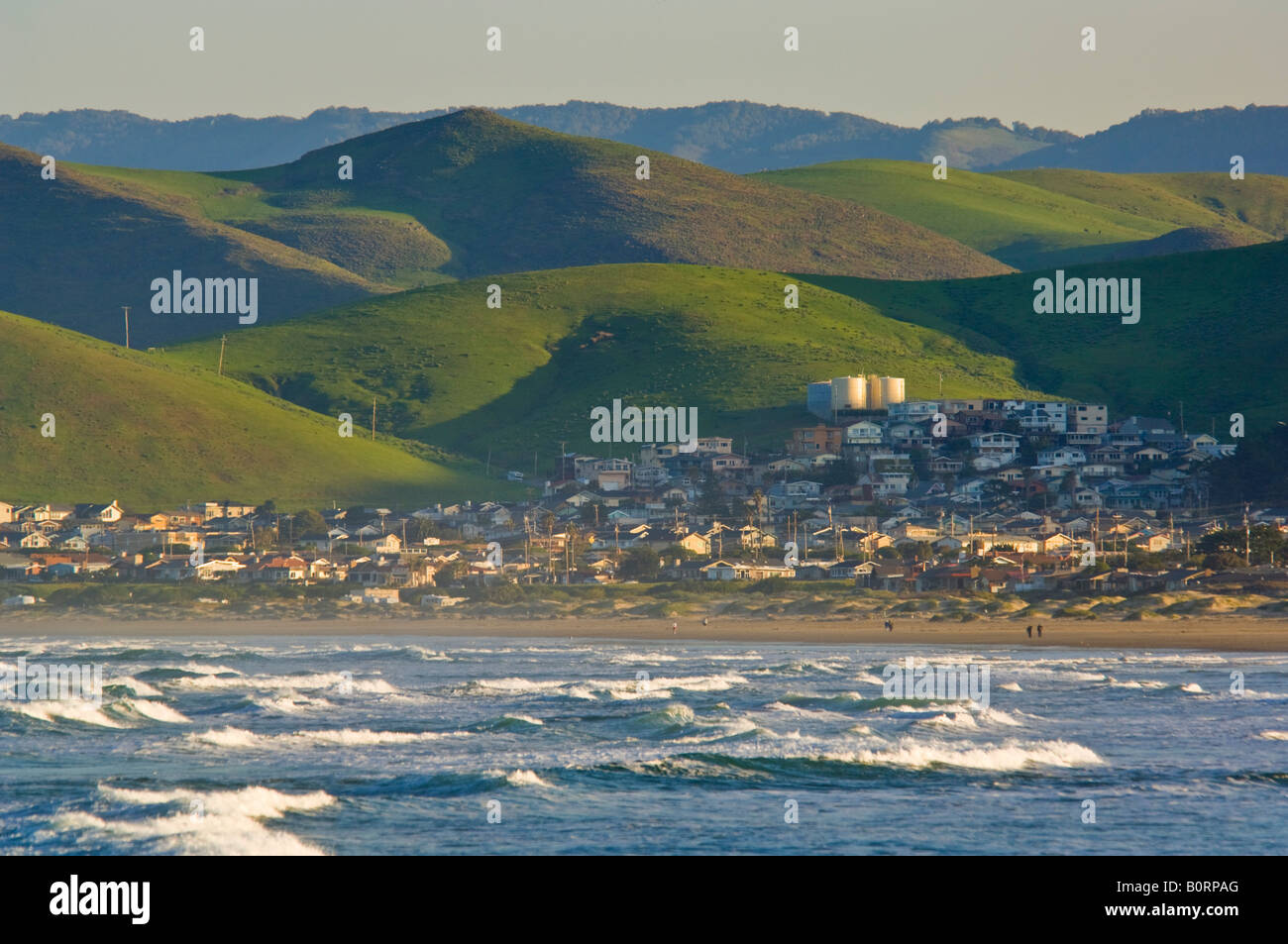 Wellen brechen unter grünen Hügeln im Frühjahr bei Morro Strand State Beach Morro Bay, Kalifornien Stockfoto