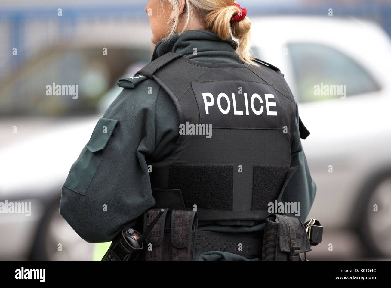 blonde PSNI Dienst Nordirland Polizistin auf Streife mit Stab Weste und sidearm Stockfoto