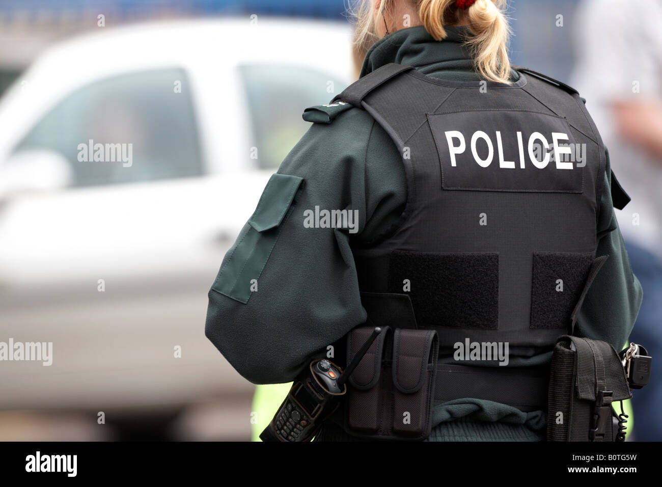 blonde PSNI Dienst Nordirland Polizistin auf Streife mit Stab Weste und sidearm Stockfoto