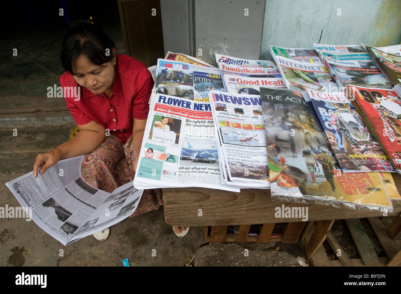 Eine Frau liest Zeitung in einer Zeitung stand in Yangon Myanmar, Mai Birma 2008 Stockfoto