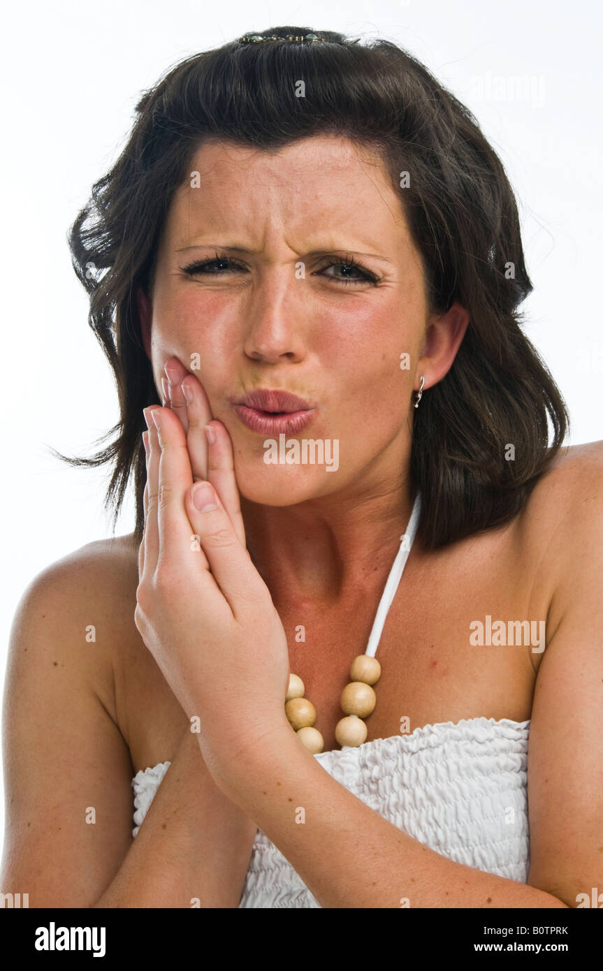 Eine junge Frau, die leiden unter schmerzhaften Zahnschmerzen oder Mund Geschwür Typ Unpäßlichkeit reiben ihre Wange zur Schmerzlinderung, UK Stockfoto