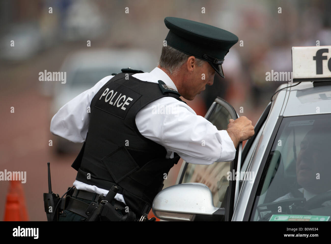 Die PSNI Polizei Nordirland Polizisten sergeant Offizier auf Patrouille im Gespräch mit einem Taxifahrer auf Routine Verkehr Pflicht in Großbritannien Stockfoto