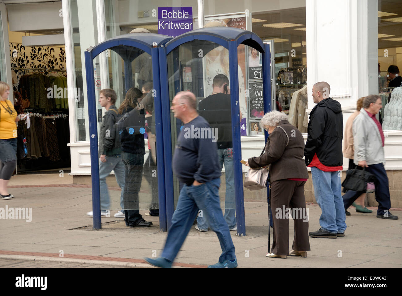 City Centre Street Furniture - Menschen warten und öffentliche Telefone mit Stockfoto