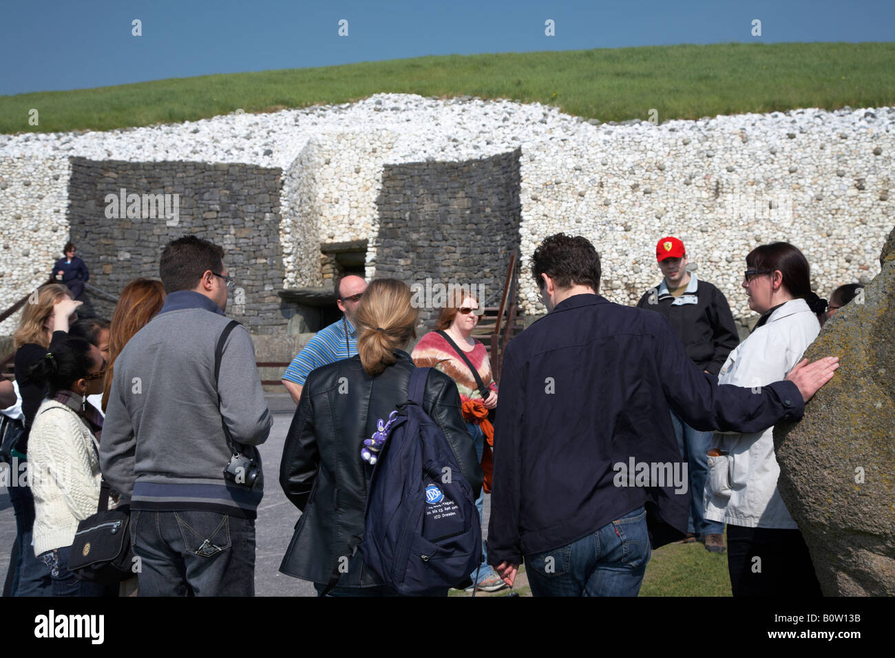 Reiseführer mit Gruppe von Touristen außerhalb der megalithischen Durchgang Grab Newgrange, County Meath, Irland Stockfoto