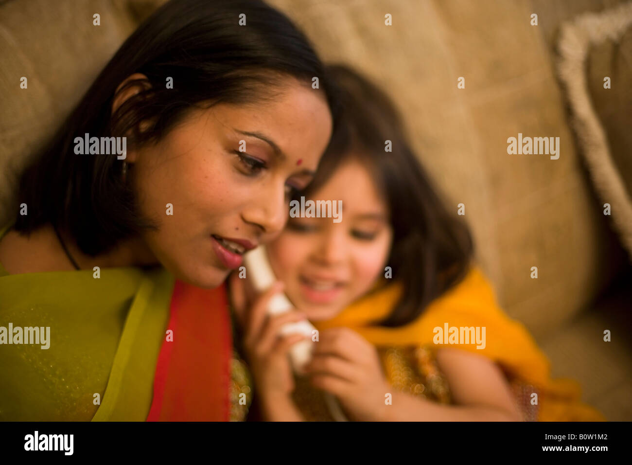Pakistanische Mutter und Tochter Mischlinge in Tracht Telefon Zuhause Stockfoto