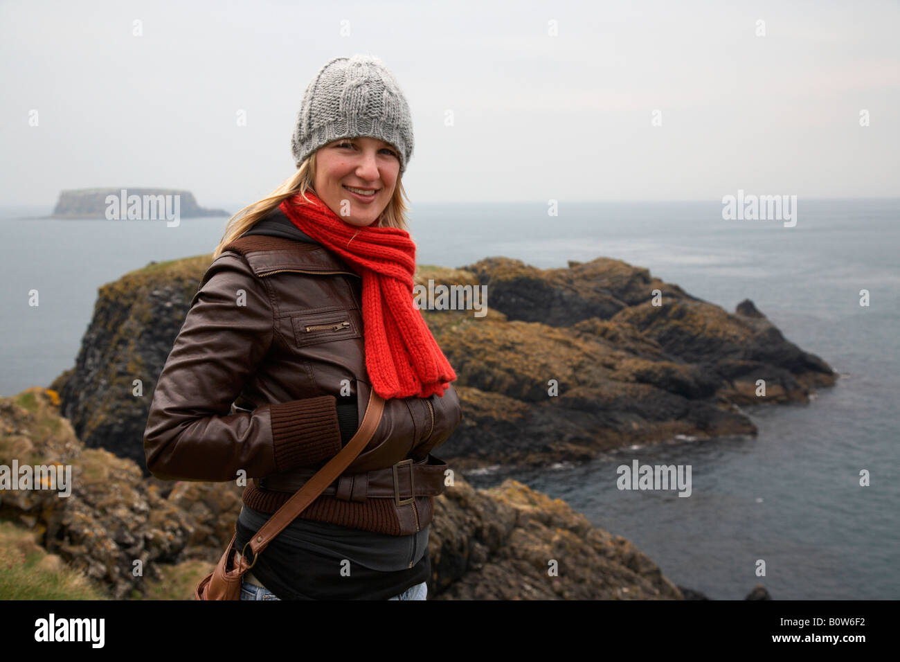 kalten weibliche Touristen stehen auf Carrick eine Rede-Insel auf der die Grafschaft Antrim Küste Nordirland an einem kalten bewölkten Tag Stockfoto