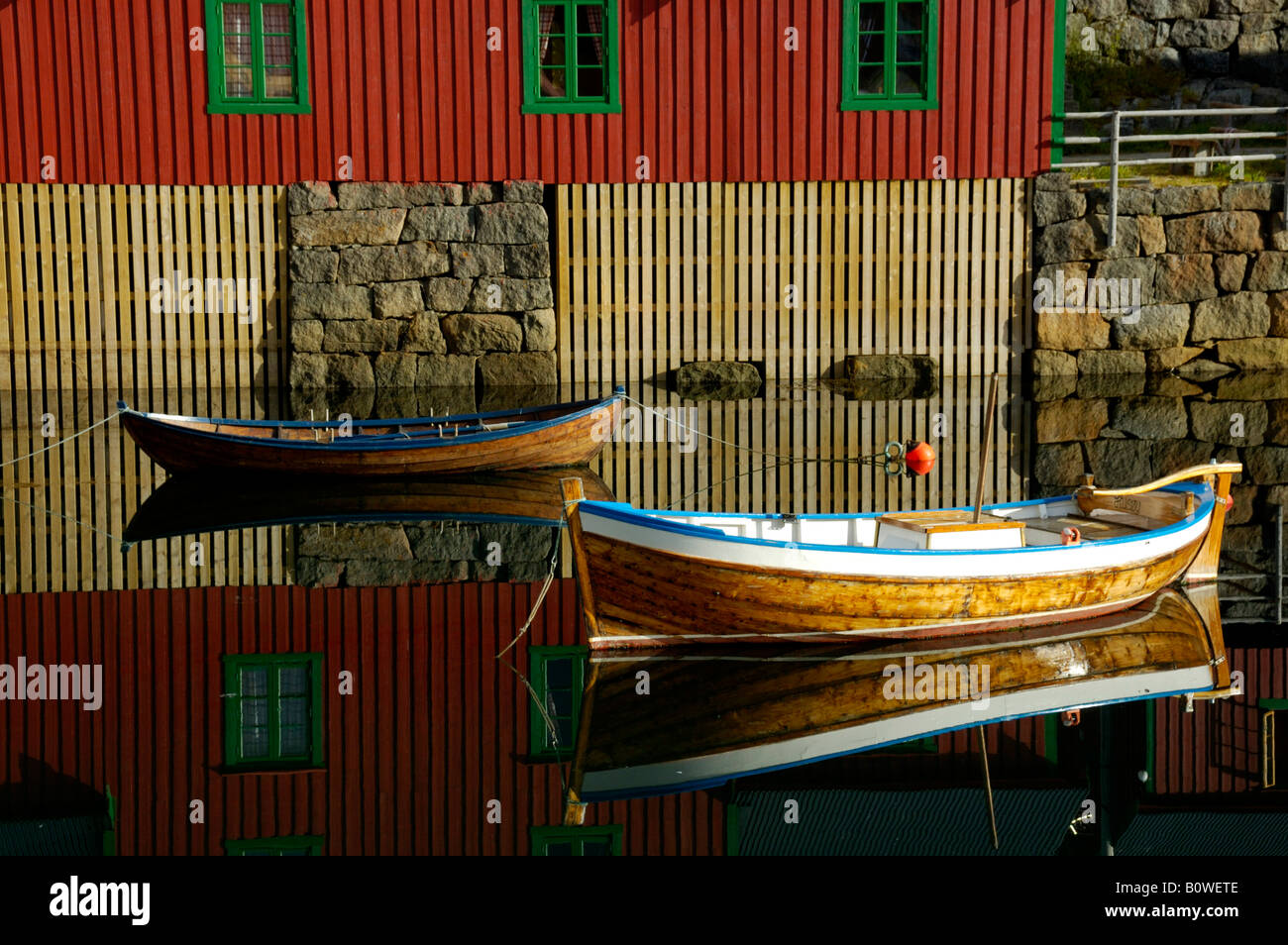 Rot lackierte Holzhaus und Ruderboote spiegelt sich im Wasser, Stamsund, Vestvagoey, Lofoten, Norwegen, Skandinavien Stockfoto