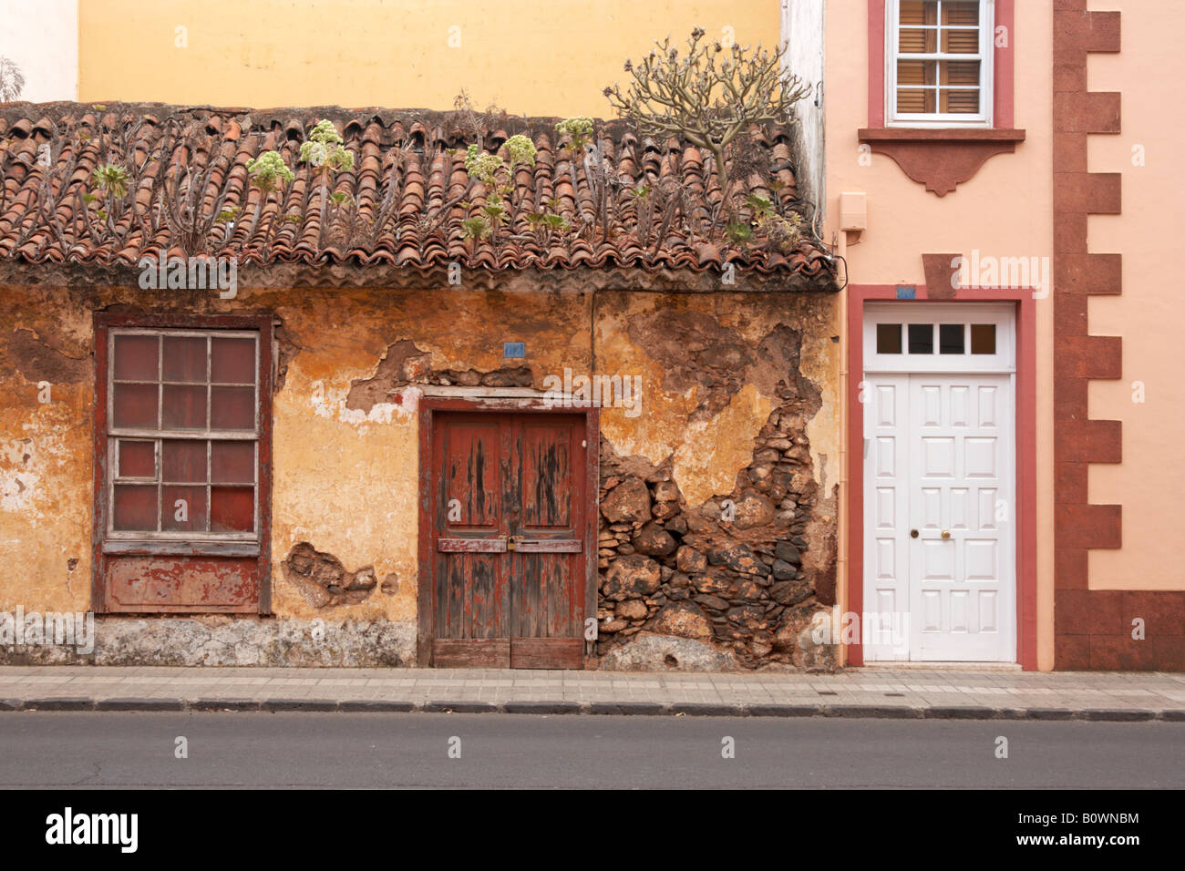 Altes Steinhaus mit Ziegeldach neben neuen Haus mit UPVC Tür und Fenster in La Laguna auf Teneriffa. Stockfoto