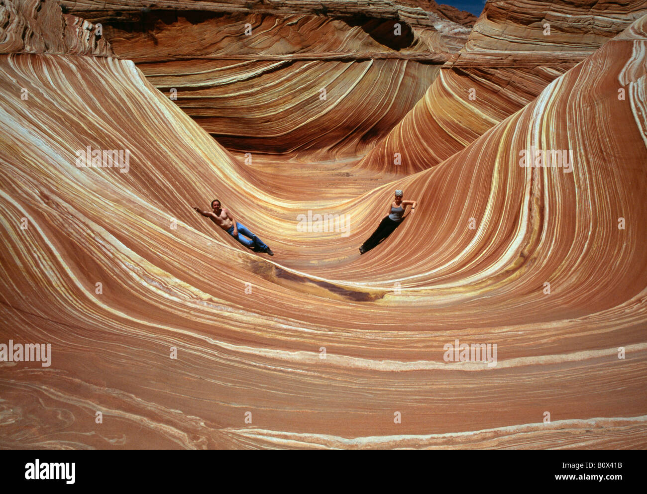 Zwei Menschen liegen in The Wave, Coyote Buttes, Paria Canyon-Vermilion Cliffs Wilderness, Arizona, USA Stockfoto