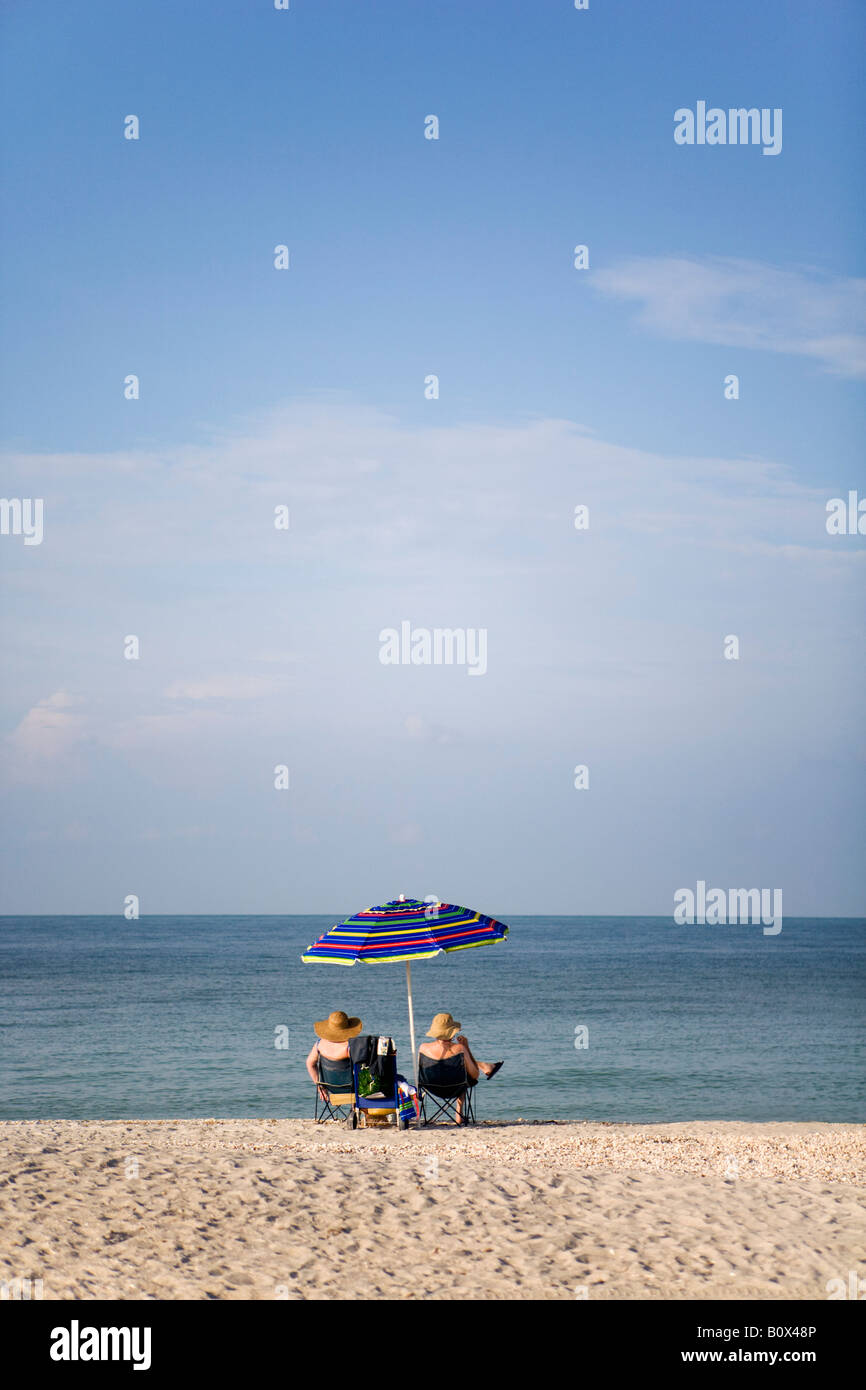 Zwei Menschen sitzen an einem Strand und Blick auf das Meer Stockfoto