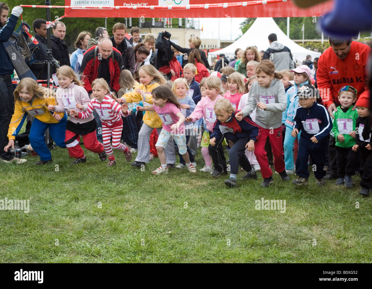 Kinder im Vorschulalter bis zu 6 Jahren auf der Startlinie mit Startnummern auf ein Rennen starten Stockfoto