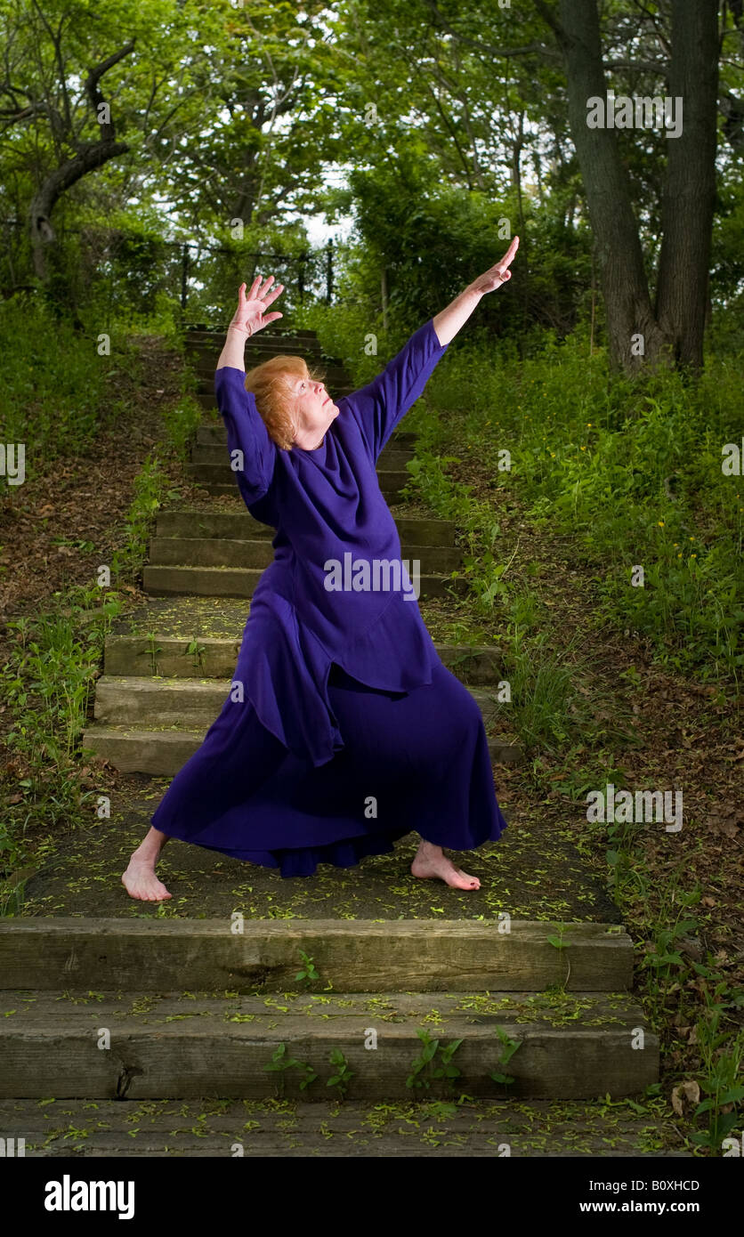 Eine Frau, die Durchführung von stretching-Techniken und Yoga außerhalb in einem Waldgebiet mit Schritten Stockfoto