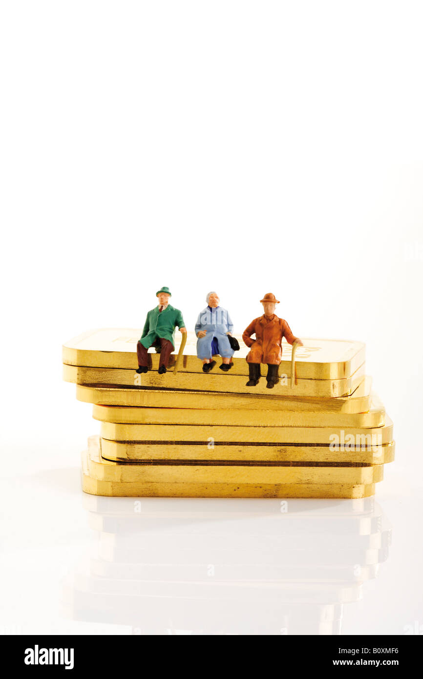 Kunststoff-Figuren sitzen auf Goldbarren Stockfoto