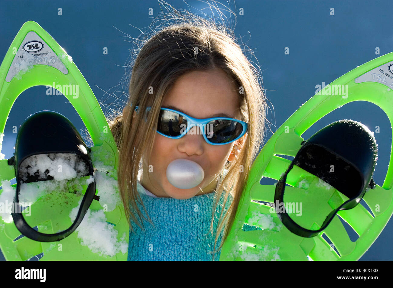 Mädchen mit grünen Skischuhe macht eine Kaugummi-Blase, Frankreich, Alpen Stockfoto
