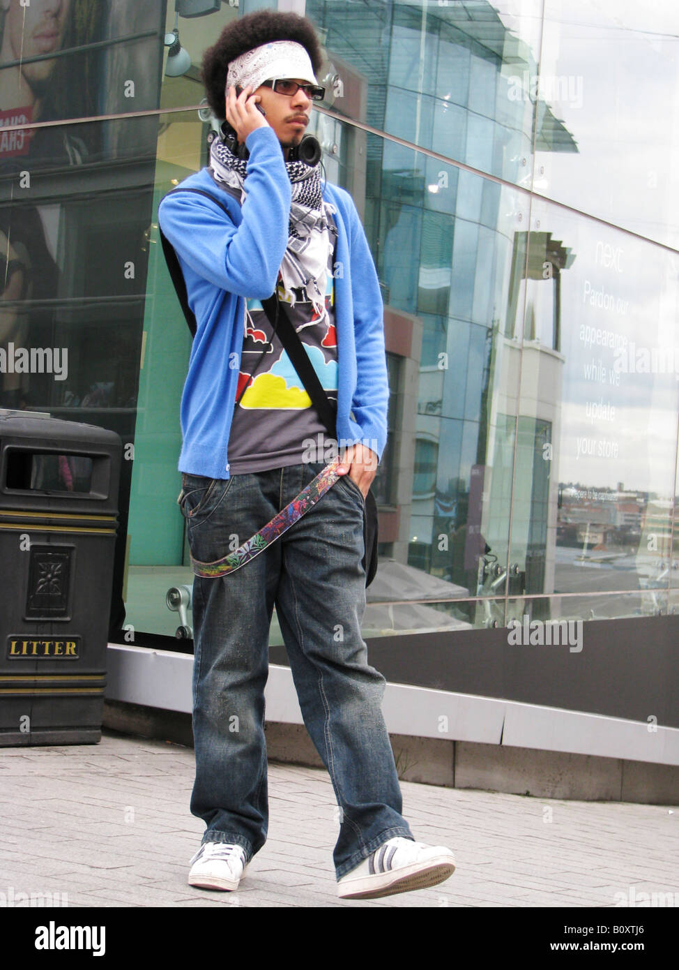 Junger Mensch mit Stirnband und hippe Kleidung spricht über sein Handy im  Zentrum Stadt, England, Birmingham Stockfotografie - Alamy