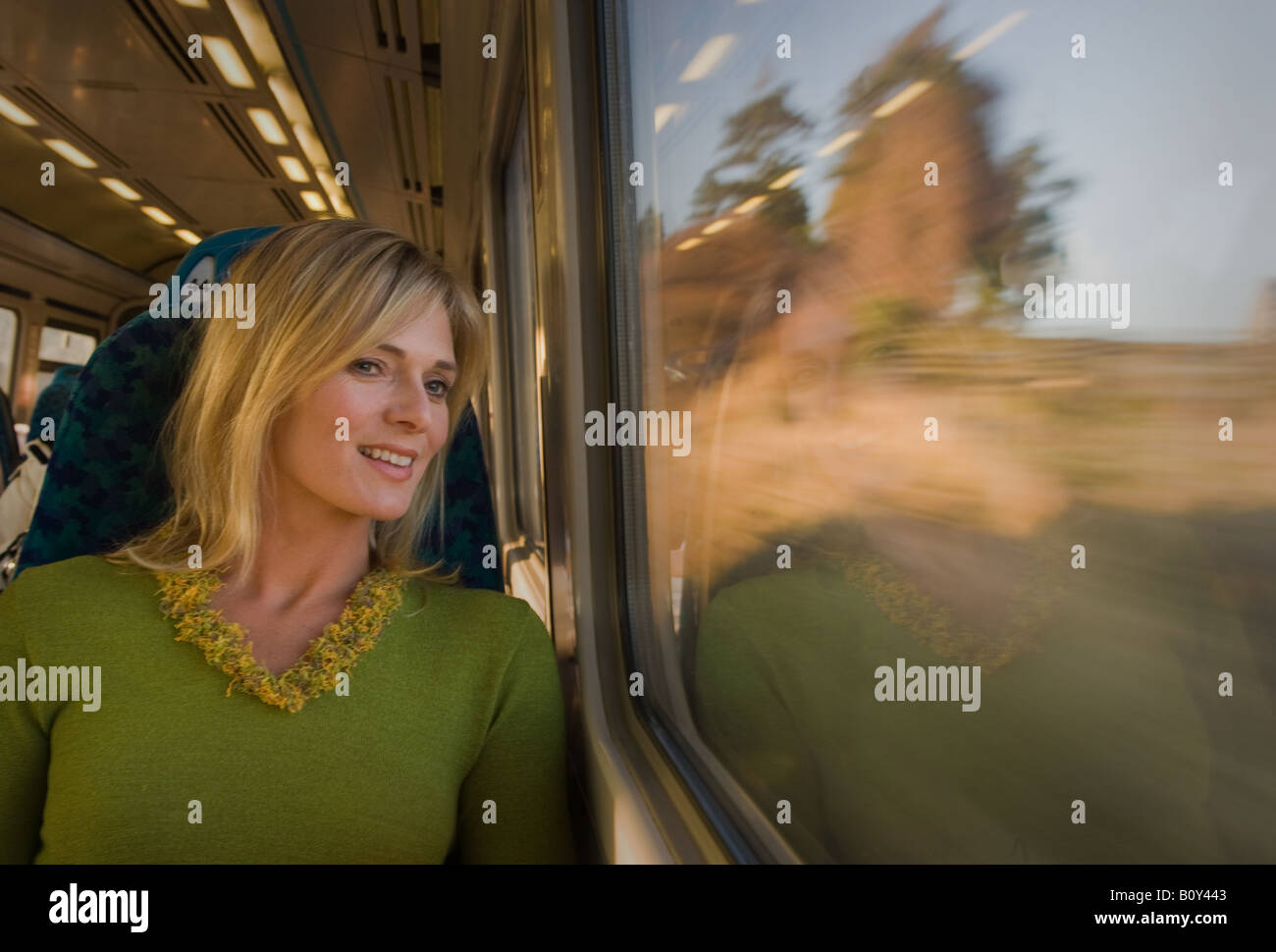 Junge Dame blickte und lächelnd aus beweglichen Zugfenster. Stockfoto