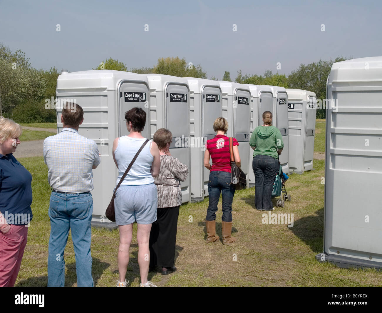 Menschen Schlange, um temporäre WC-Anlagen zu einem fairen Land verwenden Stockfoto