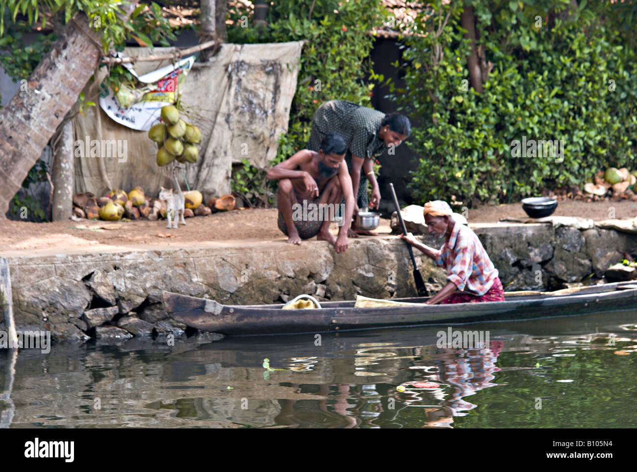 Indien KERALA indischen Ehepaar Fisch vom örtlichen Fischer, der seinem Kanu entlang der Grachten von Haus zu Haus Zeilen kaufen Stockfoto