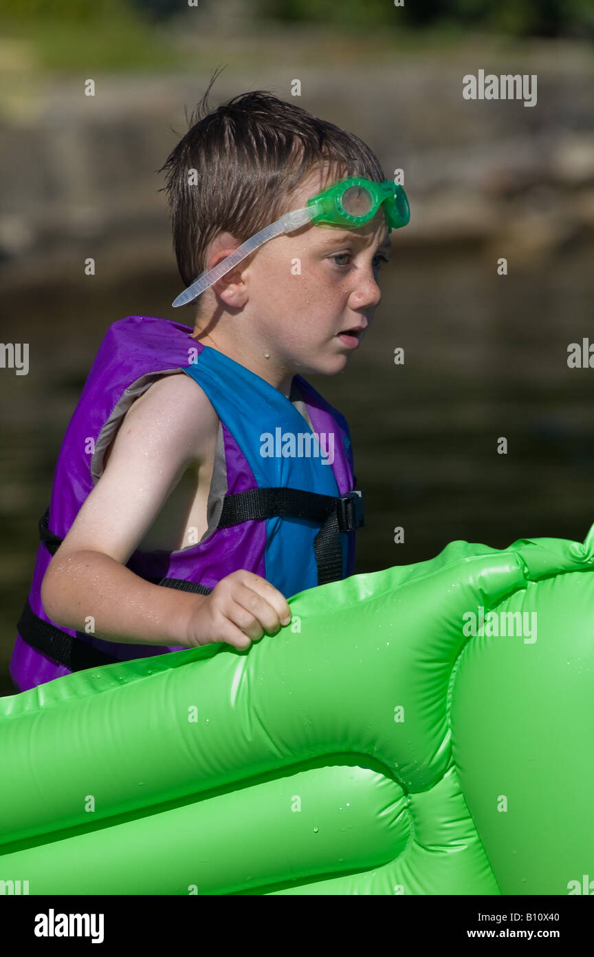 männliche junge 4-5-6 Jahre alt mit grünen Floating Floß zu schwimmen, Schutzbrille und Warnweste Stockfoto