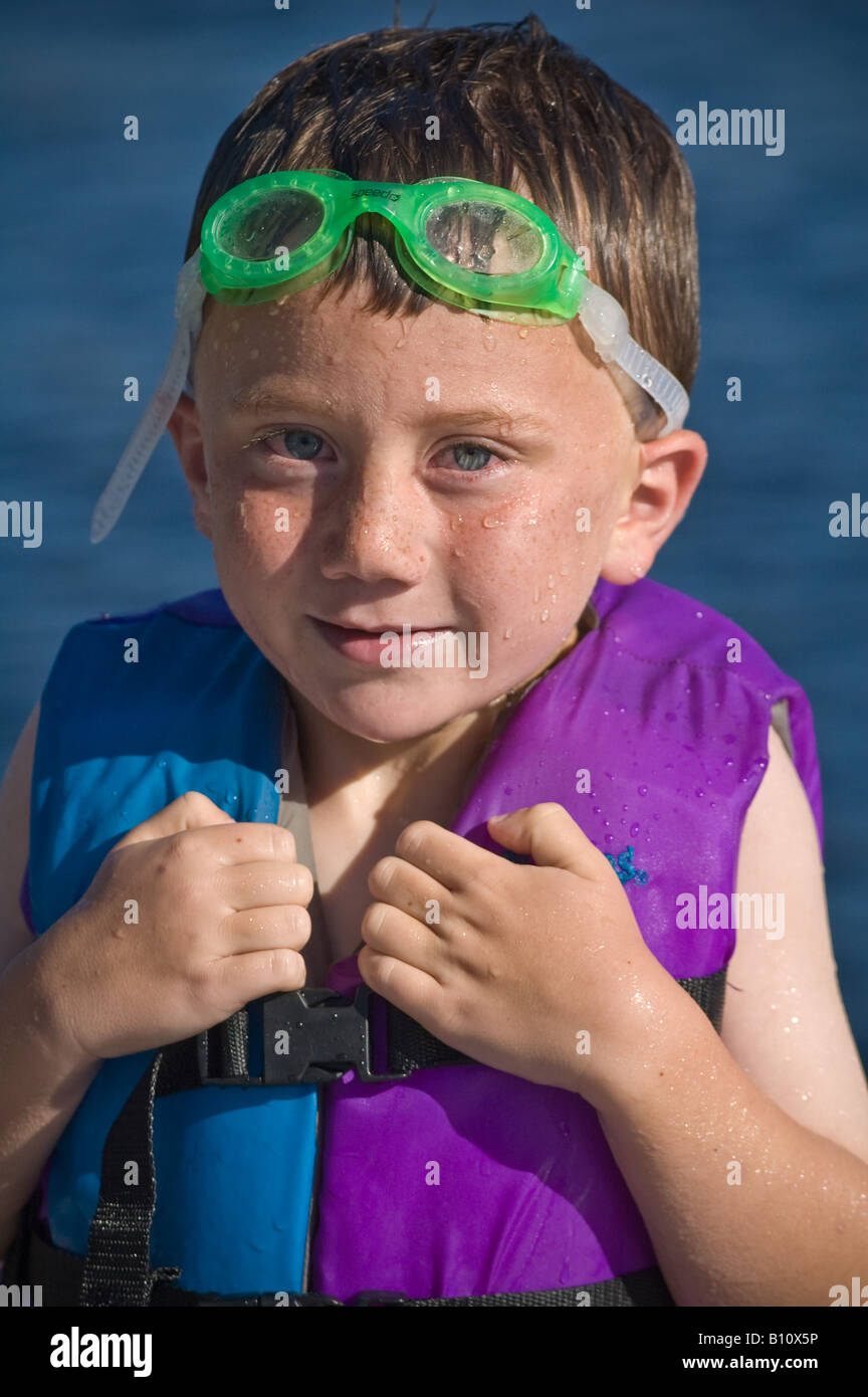 männliche junge 4-5-6 Jahre alt mit grünen Floating Floß zu schwimmen, Schutzbrille und Warnweste Stockfoto