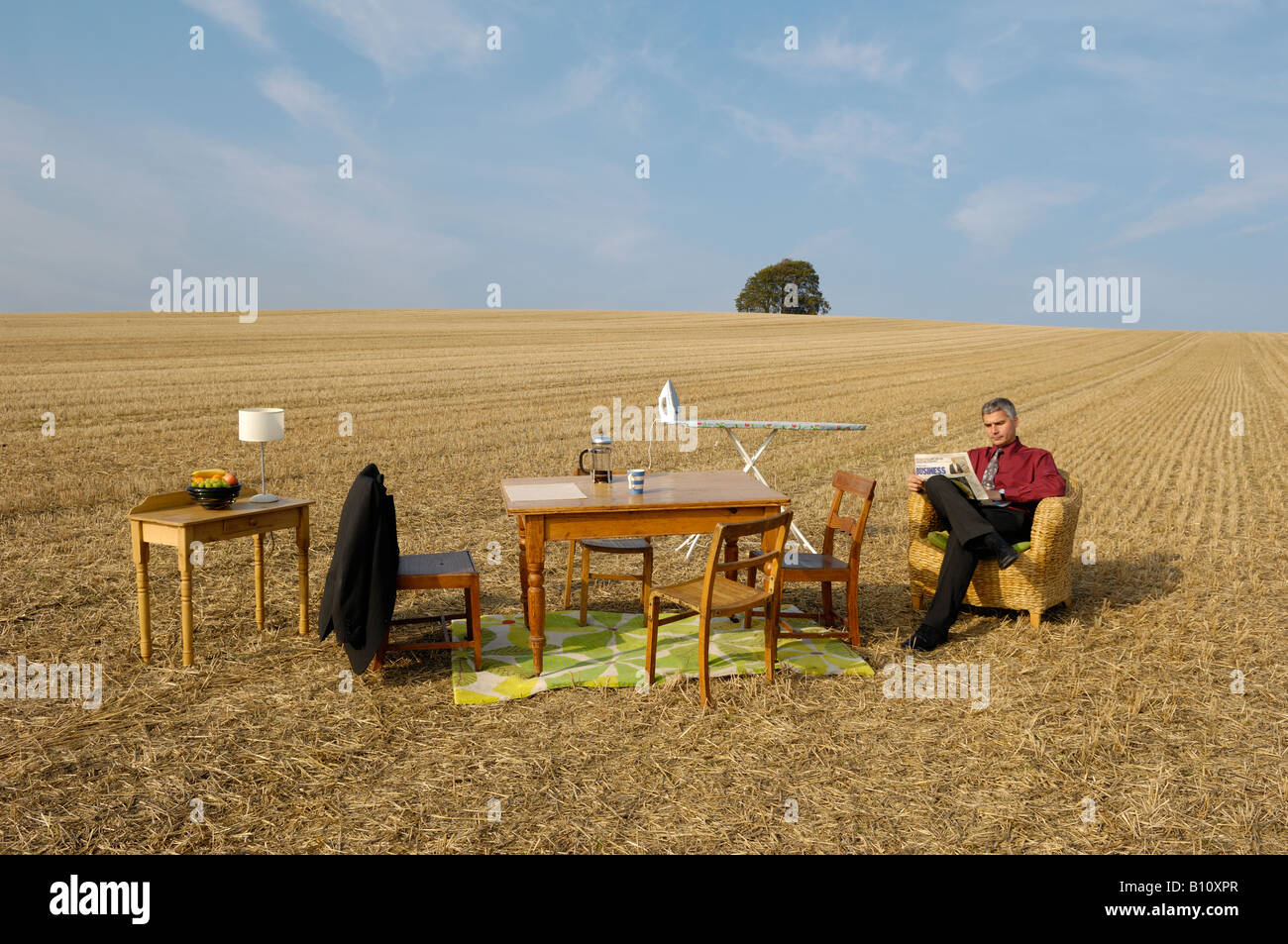 Mann sitzt auf einem Stuhl im Zimmer im freien lesen Zeitung Stockfoto