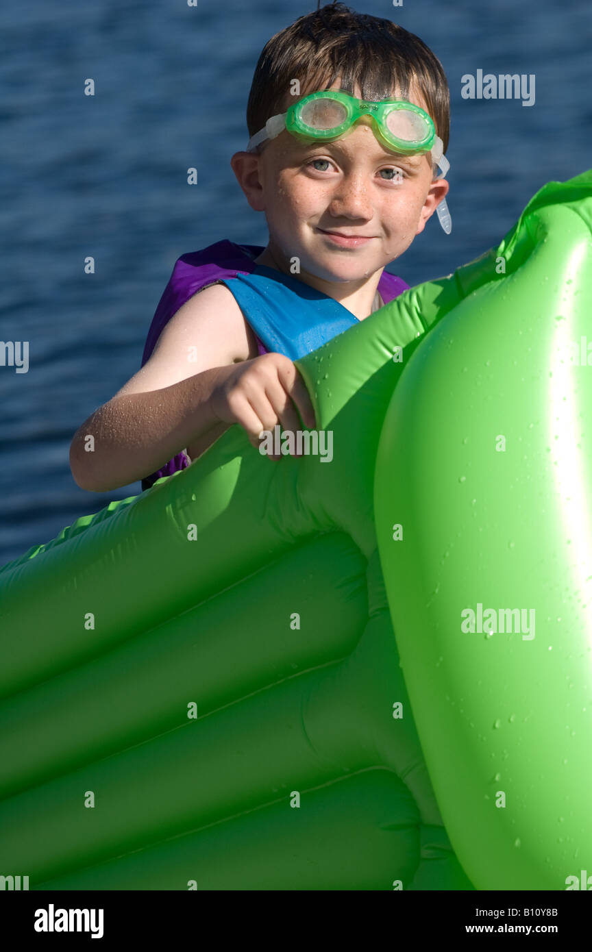 männliche junge 4-5-6 Jahre alt mit grünen Floating Floß zu schwimmen, Schutzbrille und Warnweste Stockfoto