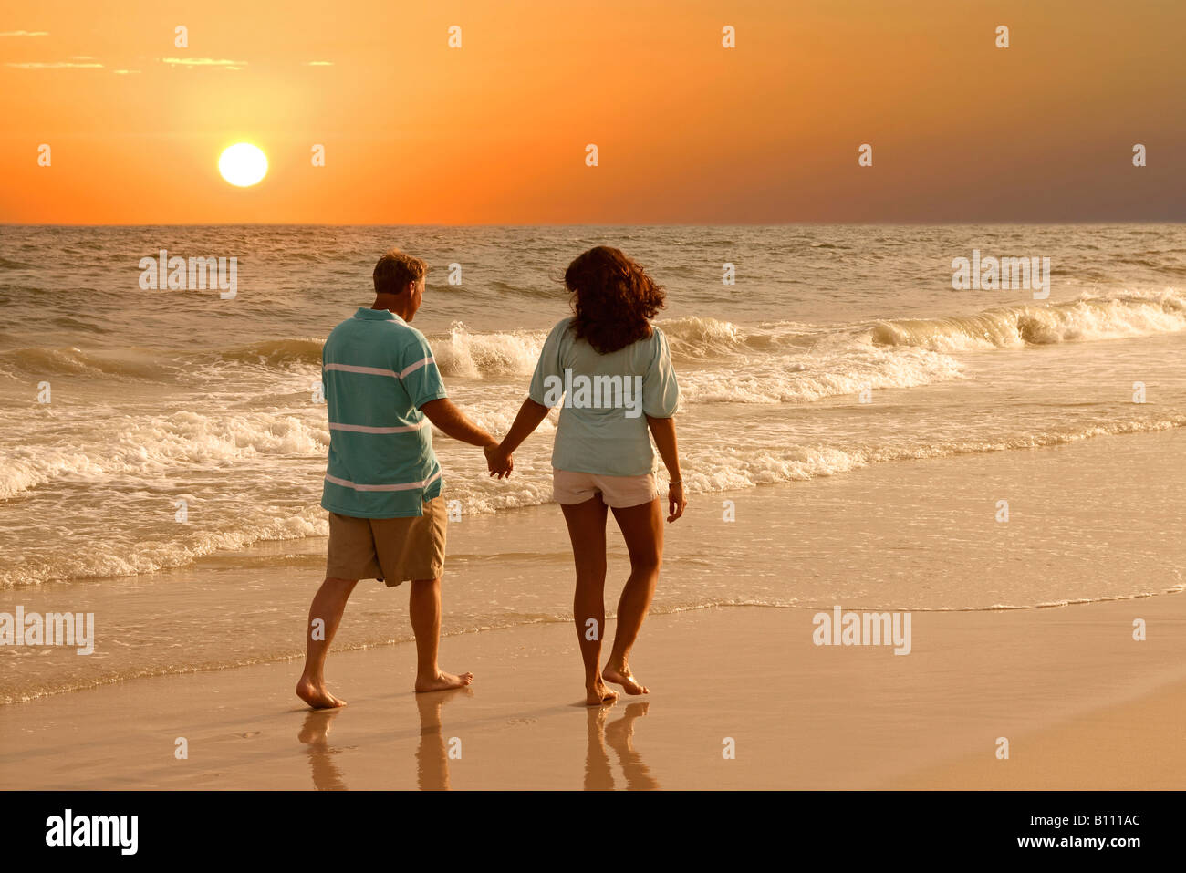 Ein paar gehen gemeinsam auf die Alabama Gulf Coast bei Sonnenuntergang Stockfoto