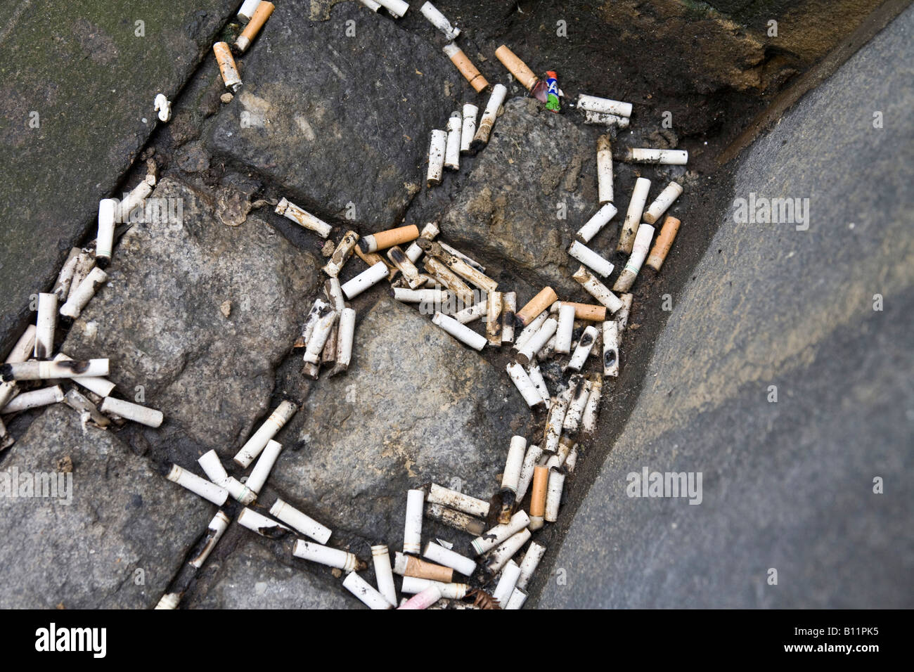 Zigaretten-enden auf einer Kopfsteinpflaster verworfen. Stockfoto