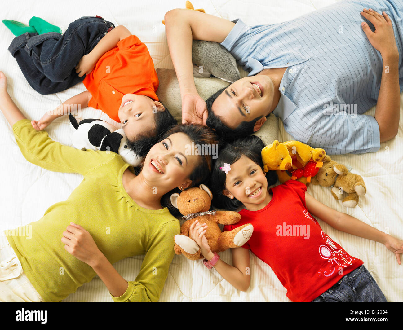 Eltern und ihre Kinder auf der Matratze liegend Stockfoto