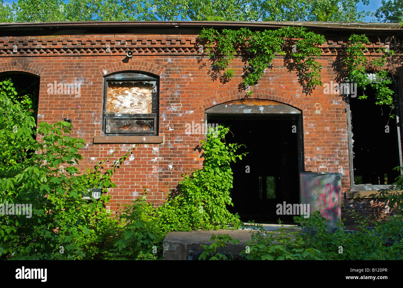 verlassen die alten Fabrikgebäude, das jetzt seine verbraucht von der Natur und ihren grünen niedergebrannt wurde. Stockfoto