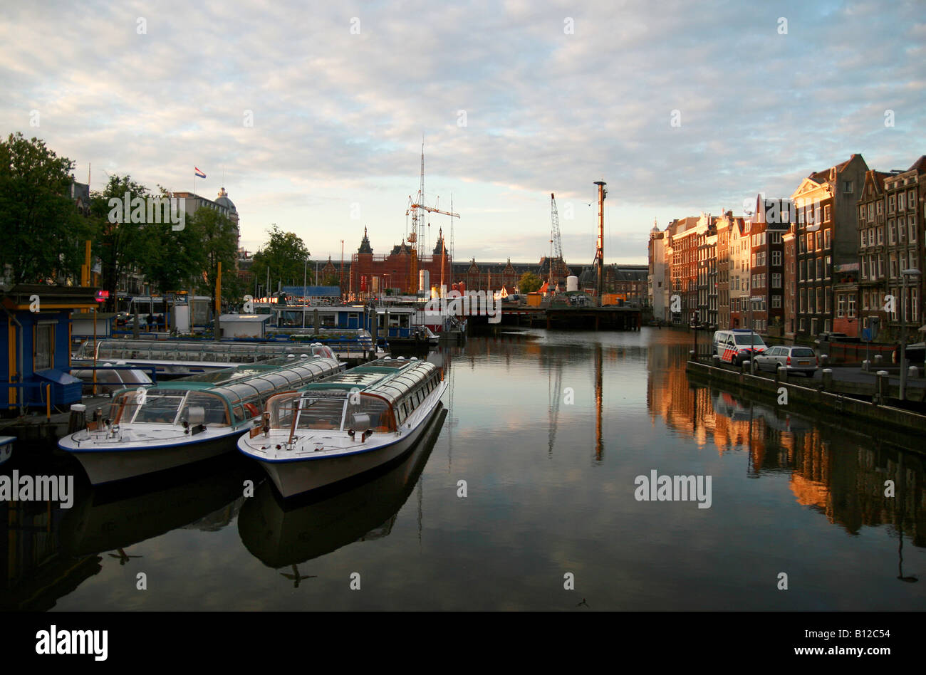 typische klassische Amsterdamer Grachtenhäuser am Damrak, in der Stadt Amsterdam, Kanal Boote im Vordergrund, Hauptbahnhof Stockfoto