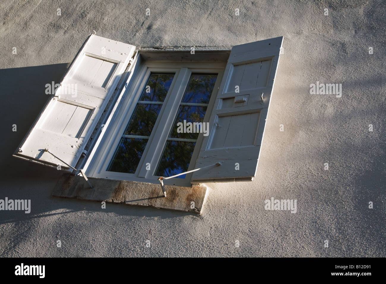 Eine Mittelmeer-französische Fensterläden Fenster mit Fensterläden geöffnet fangen das Licht am frühen Abend. Stockfoto
