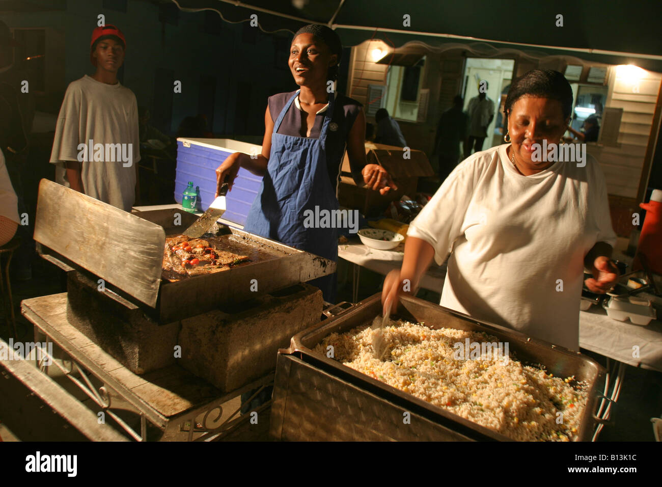 eine lokale Chef kochen bis ein Fisch braten auf dem Fischmarkt Oistins in Bridgetown, Barbados Stockfoto