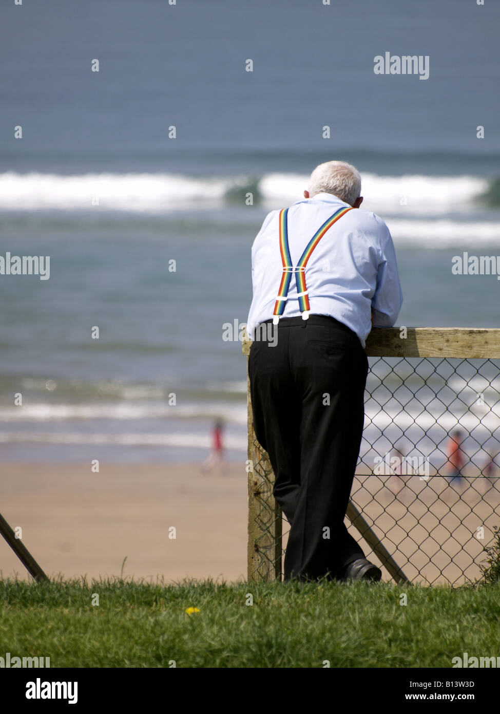 Alter Mann lehnte sich gegen den Zaun, Blick auf das Meer Stockfoto