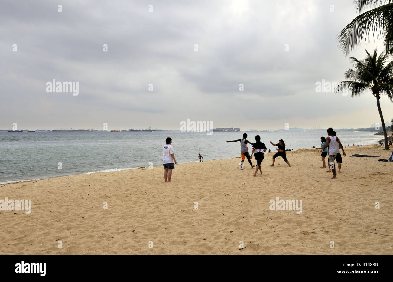 Jugendliche spielen Sepak Takraw auf dem Strandsand im East Coast Park in Singapur Stockfoto