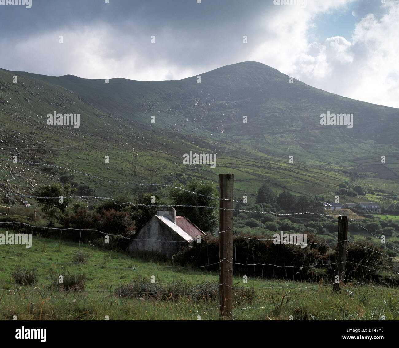 kleines altes Bauernhaus sitzt ruhig umgeben von hohen Bergen mit Nebel auf den Hügel Seiten auf Irlands Ring of kerry Stockfoto