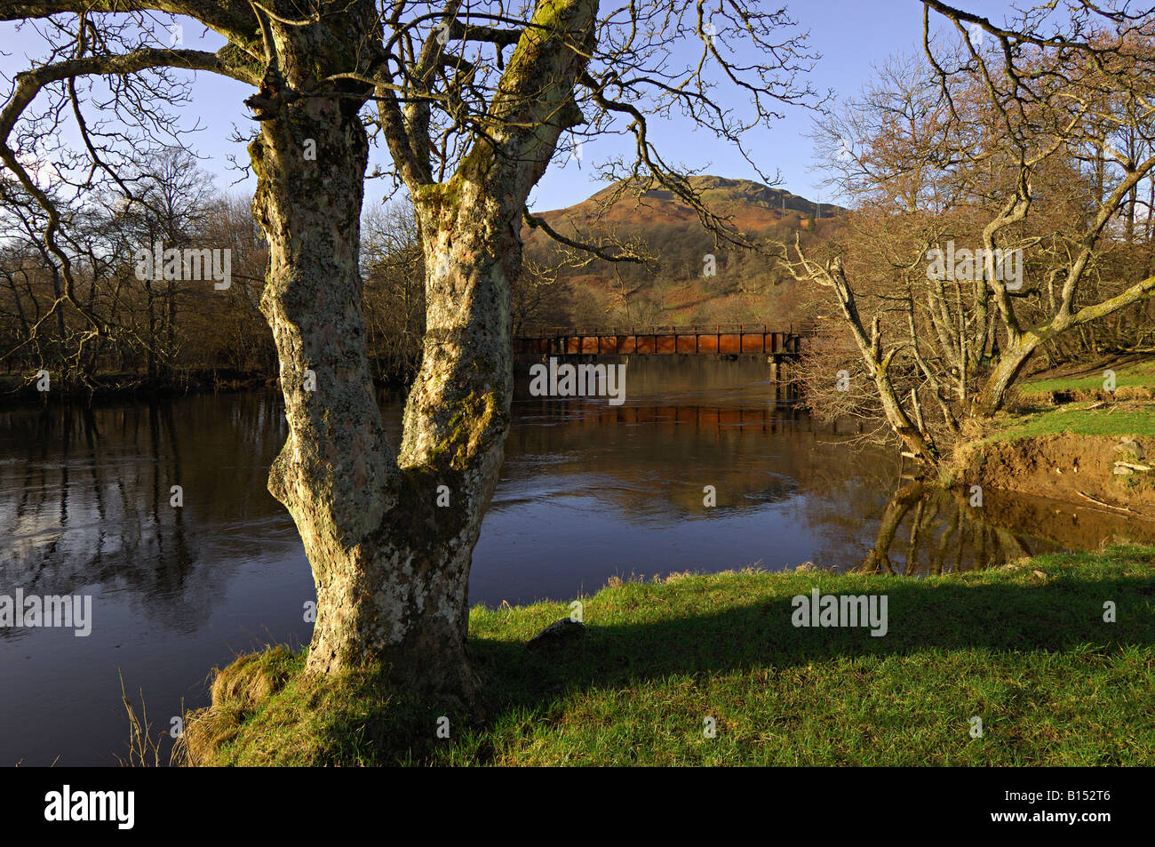 Den Bäumen gesäumten Fluss Lochay bei Killin mit ehemaligen Eisenbahnbrücke und Hügeln hinter Killin Perthshire Schottland UK Stockfoto