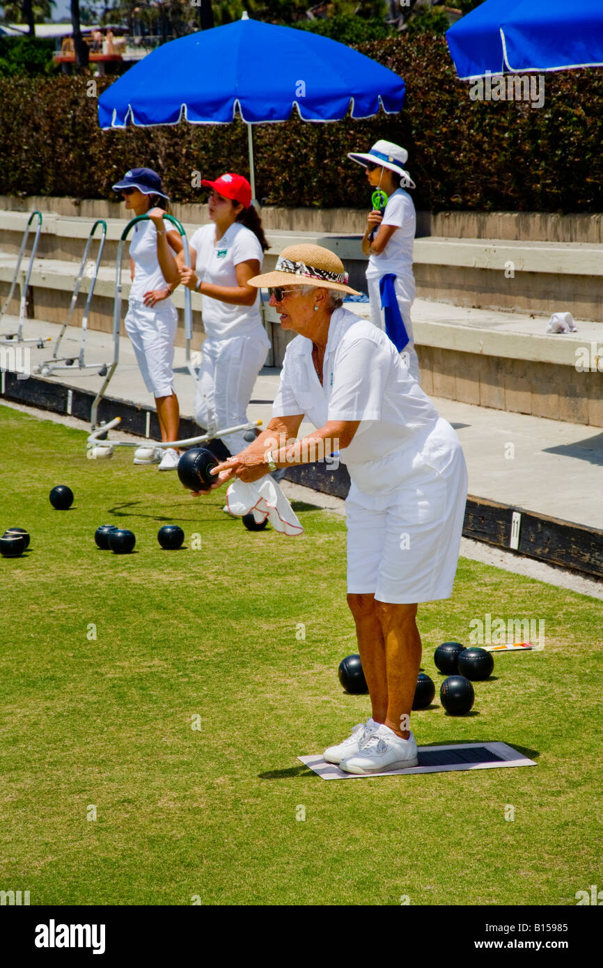 In der Verordnung weiße Uniform rollt eine Spielerin einen Schüssel Ball während einer Rasen-Bowling-Wettbewerb auf ein Bowling green Stockfoto