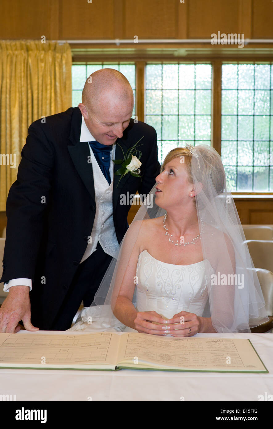 Ein frisch verheiratetes Paar haben ihre Heiratsurkunde in der Sakristei der Kirche unterzeichnet. Stockfoto