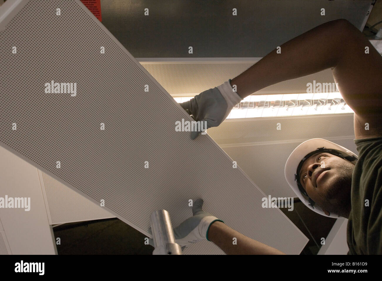 Ein Arbeiter wird eine Deckenplatte installiert. Stockfoto