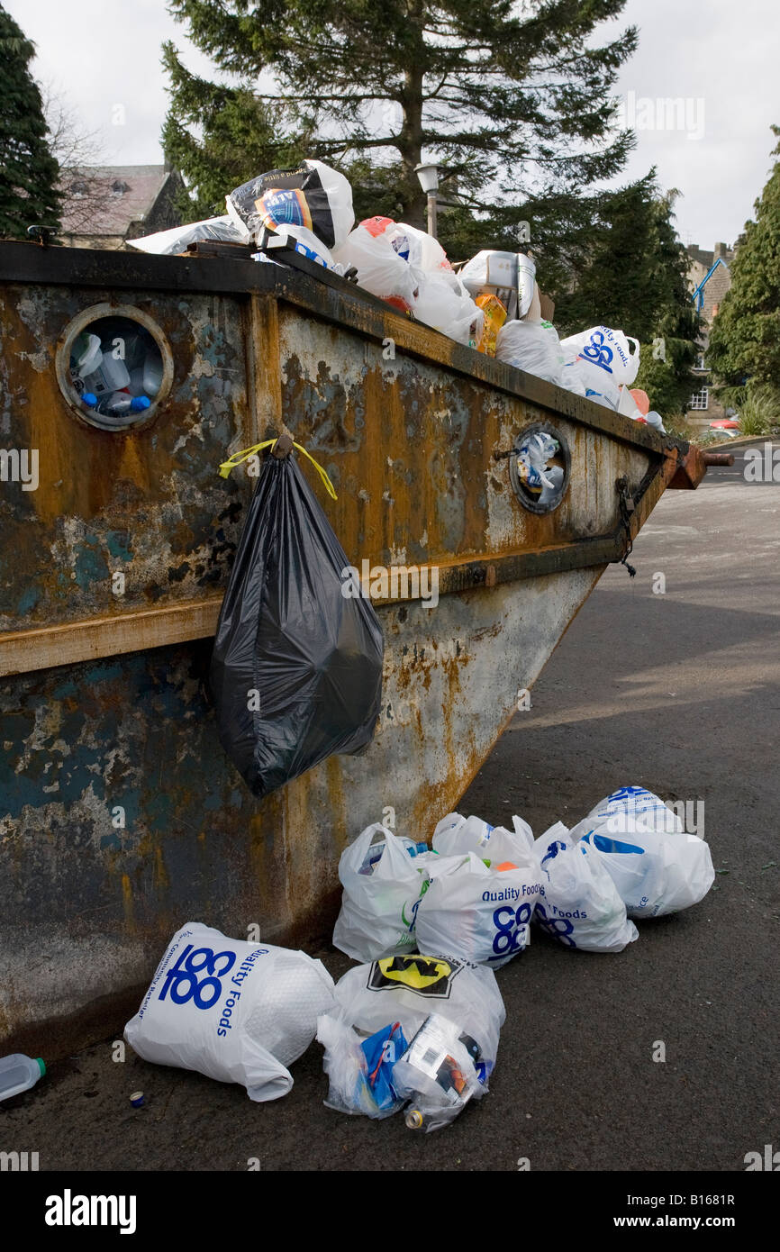 Überlastetes Recycling skip, voll nach oben (Müll und Müll weggeworfen, Plastiktüten verschmutzten Boden, Abfallproblem) - Baildon, Yorkshire, England Großbritannien. Stockfoto