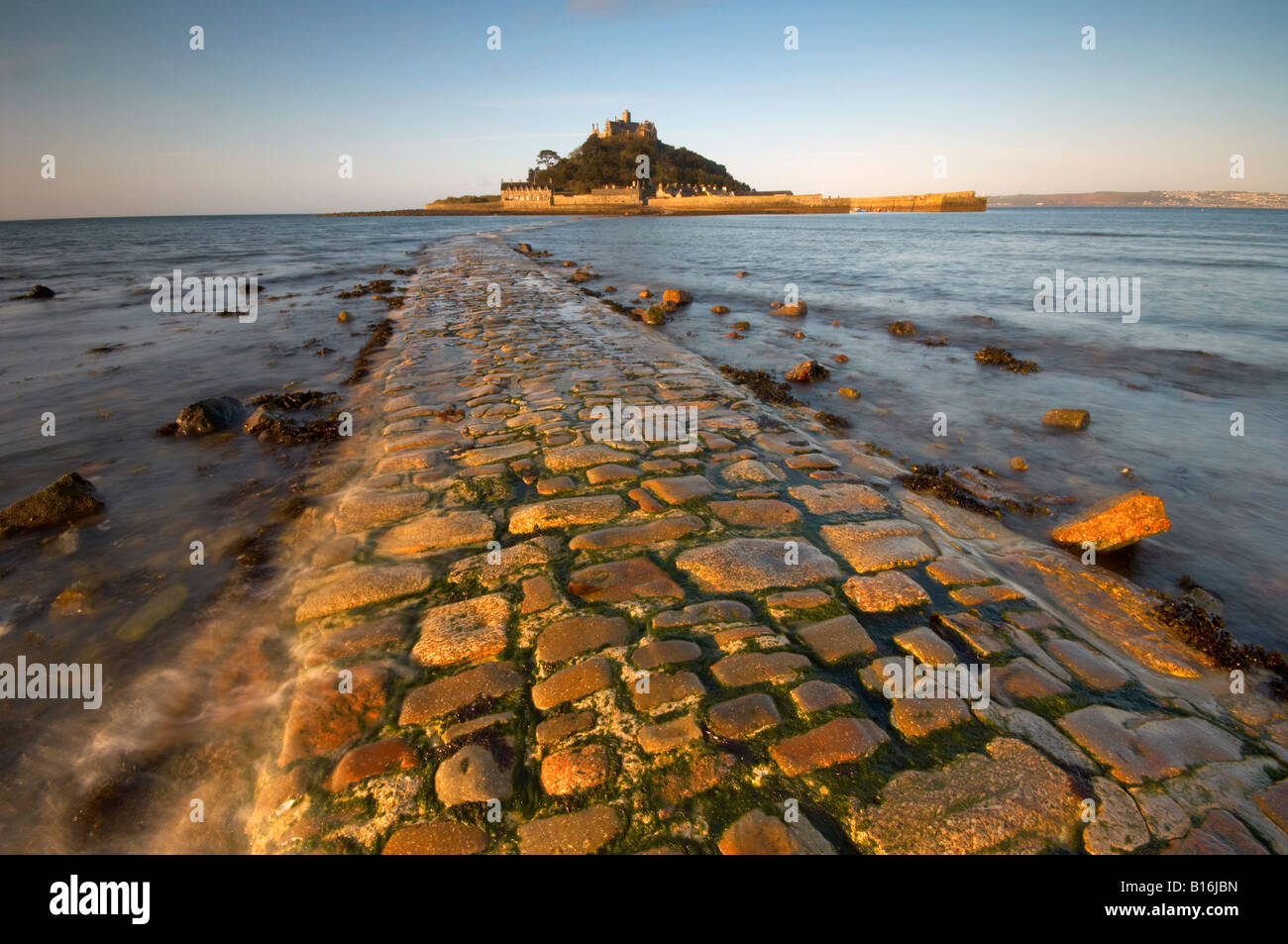 Wellen über dem der alten Steindamm führt zu St Michaels Mount im Morgengrauen Marazion Cornwall UK Stockfoto