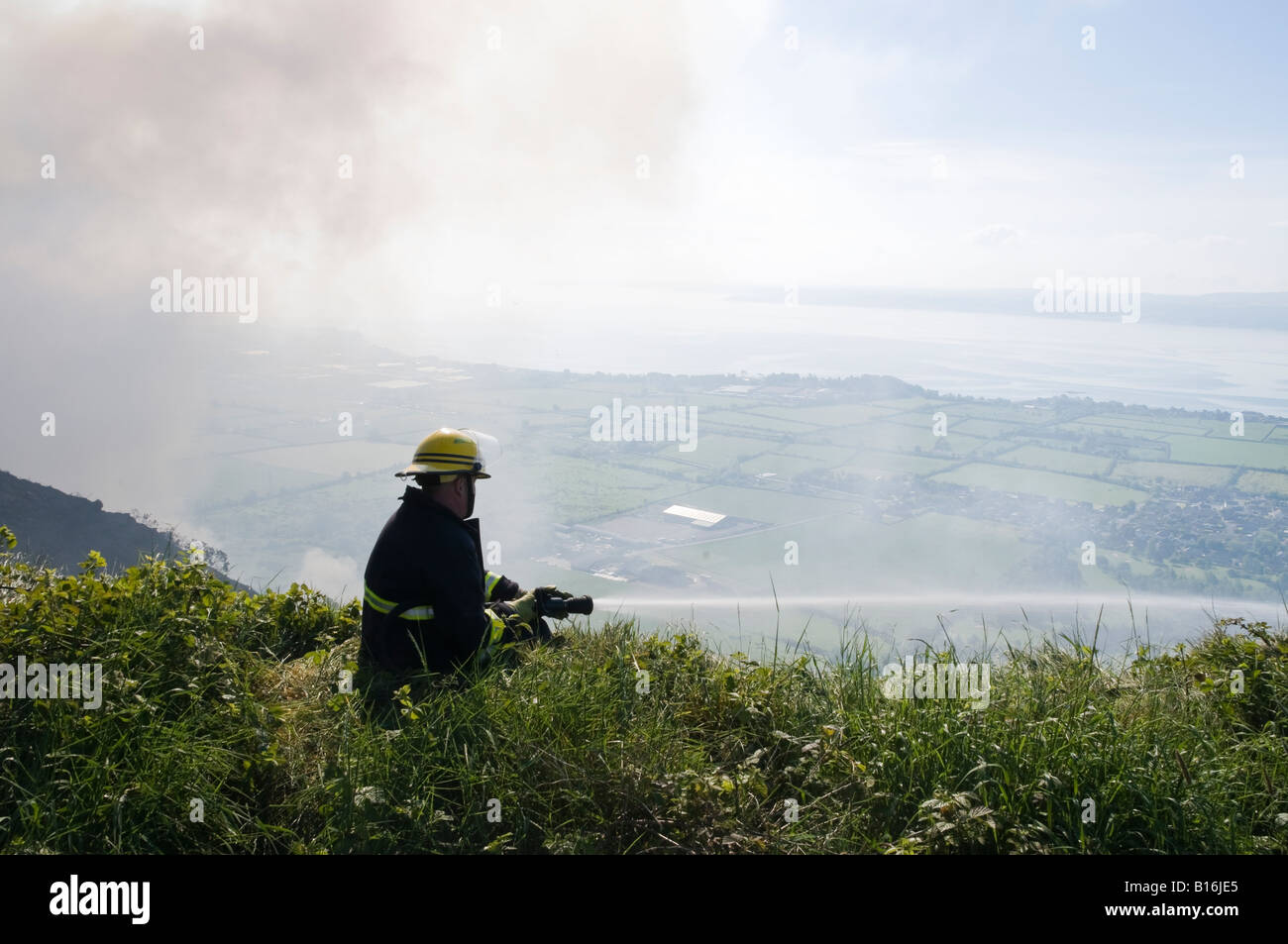 Feuerwehrmann befasst sich Ginster Feuer am Knockagh Denkmal, County Antrim Stockfoto