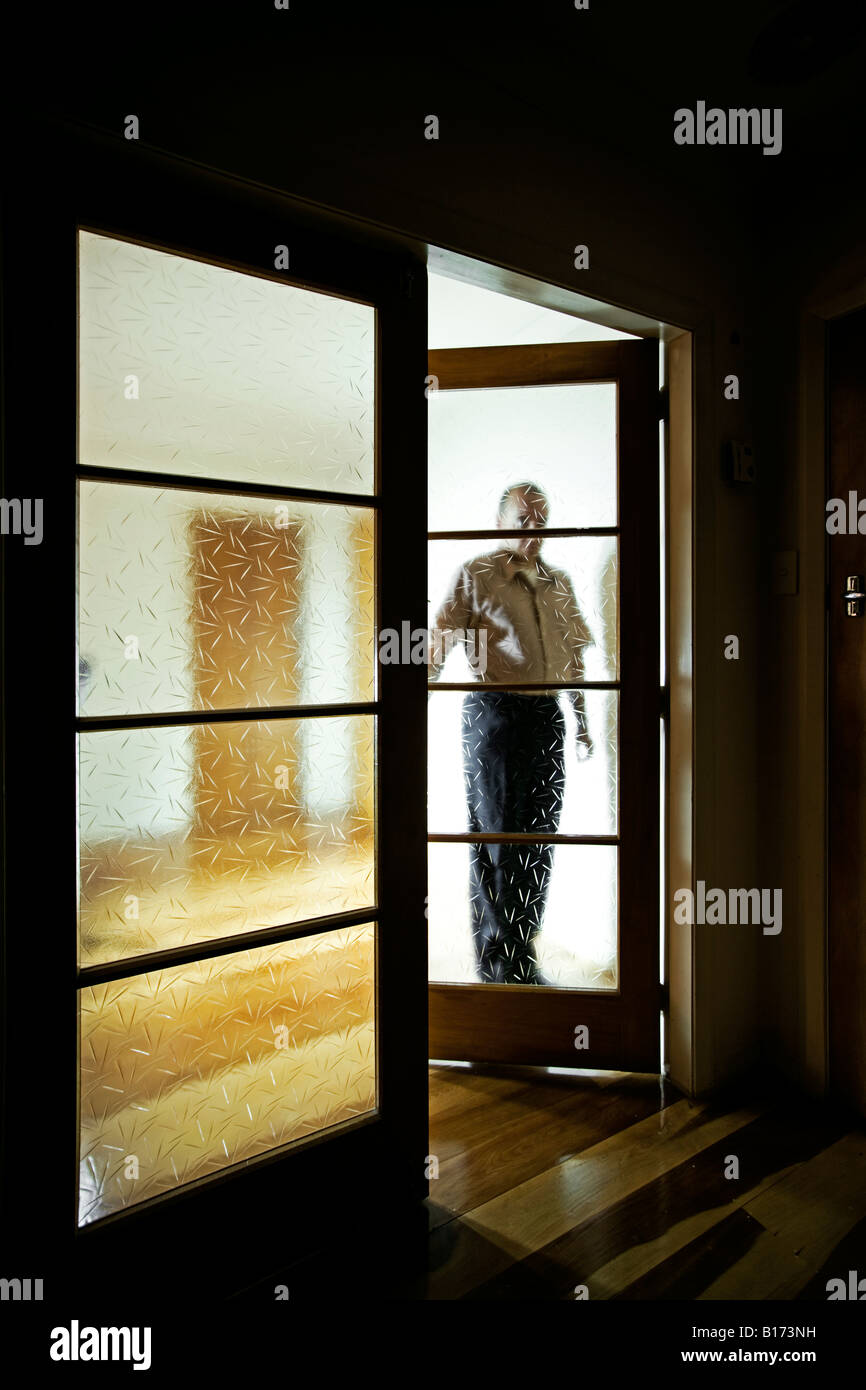 Mann von Doppelglas Innentüren in einem abgedunkelten Raum Stockfoto