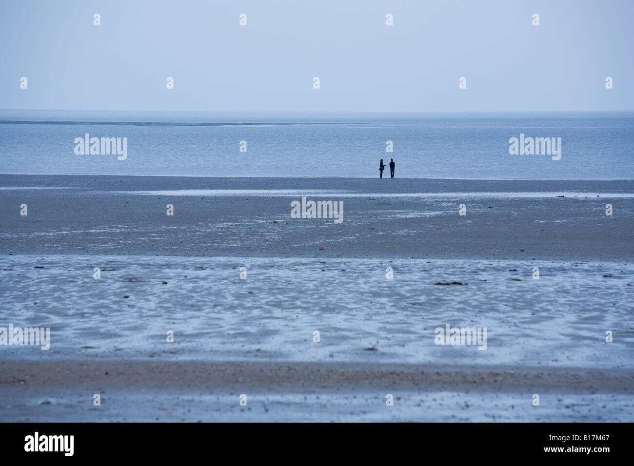 Ein paar Silhouette am Strand bei Ebbe. Monoton, kühles Blau. Allgemein Stockfoto