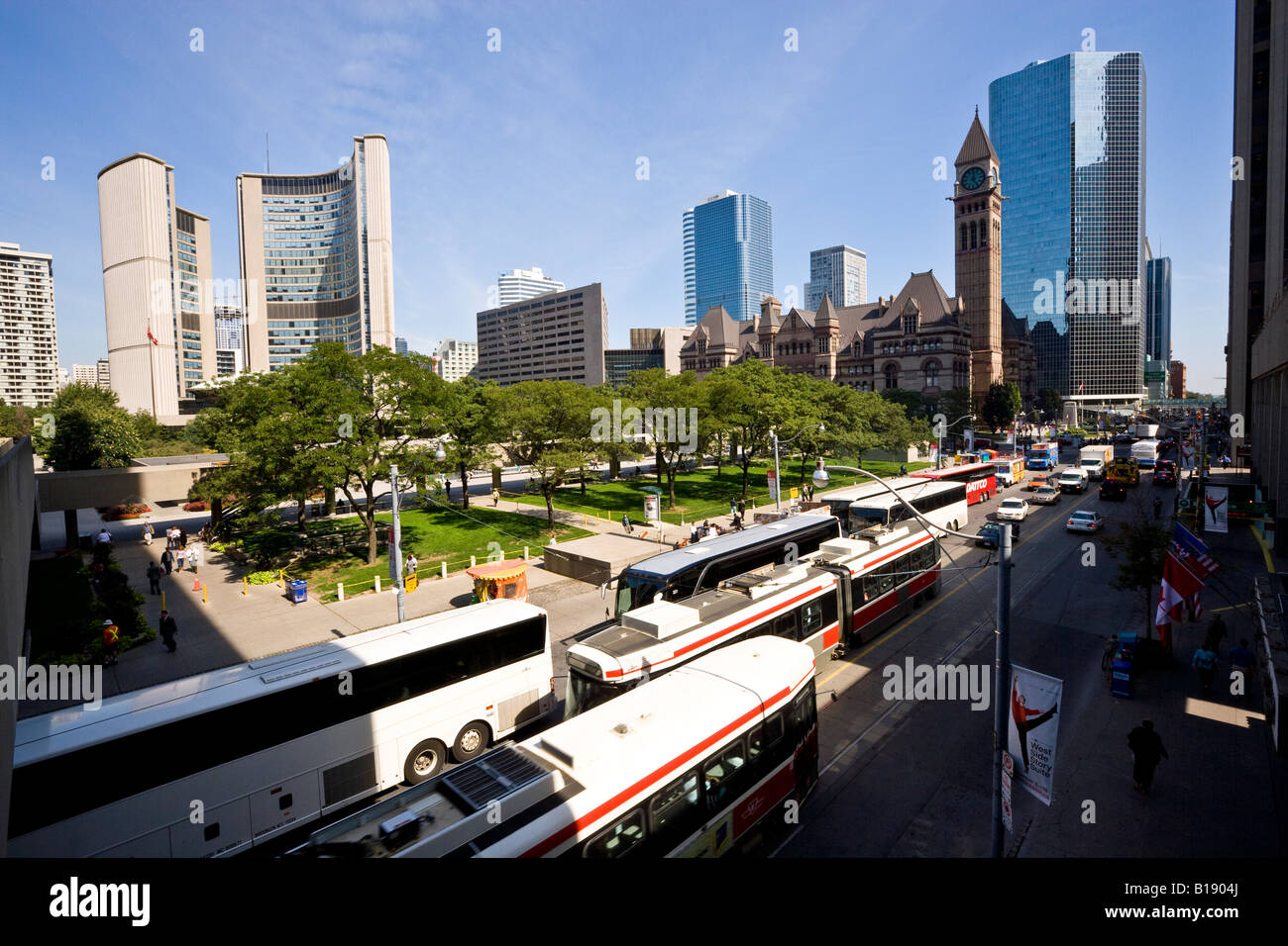 Touristenbusse und TTC Straßenbahnen auf der Queen Street vor neuen und alten Rathäuser, Toronto, Ontario, Kanada. Stockfoto