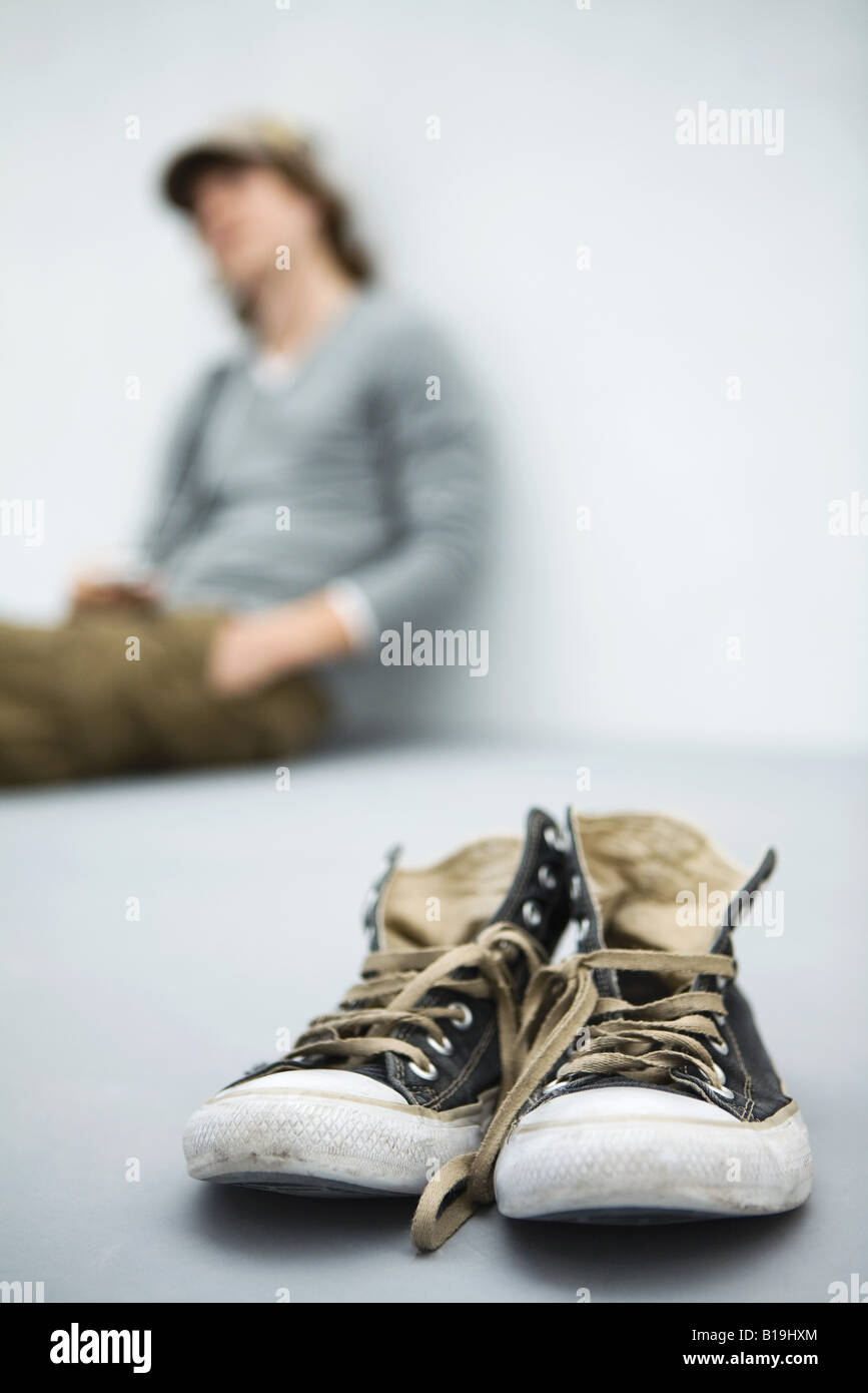 Abgenutzte Canvas-Schuhe, junge Mann sitzt im Hintergrund Stockfoto